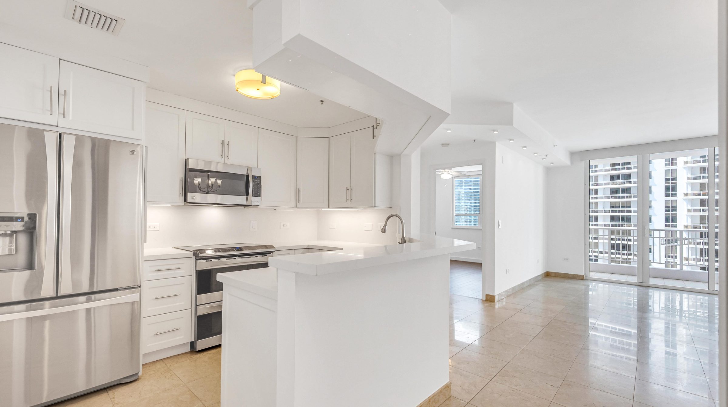 Open kitchen with stainless steel appliances, quartz counters, and a view into the living area